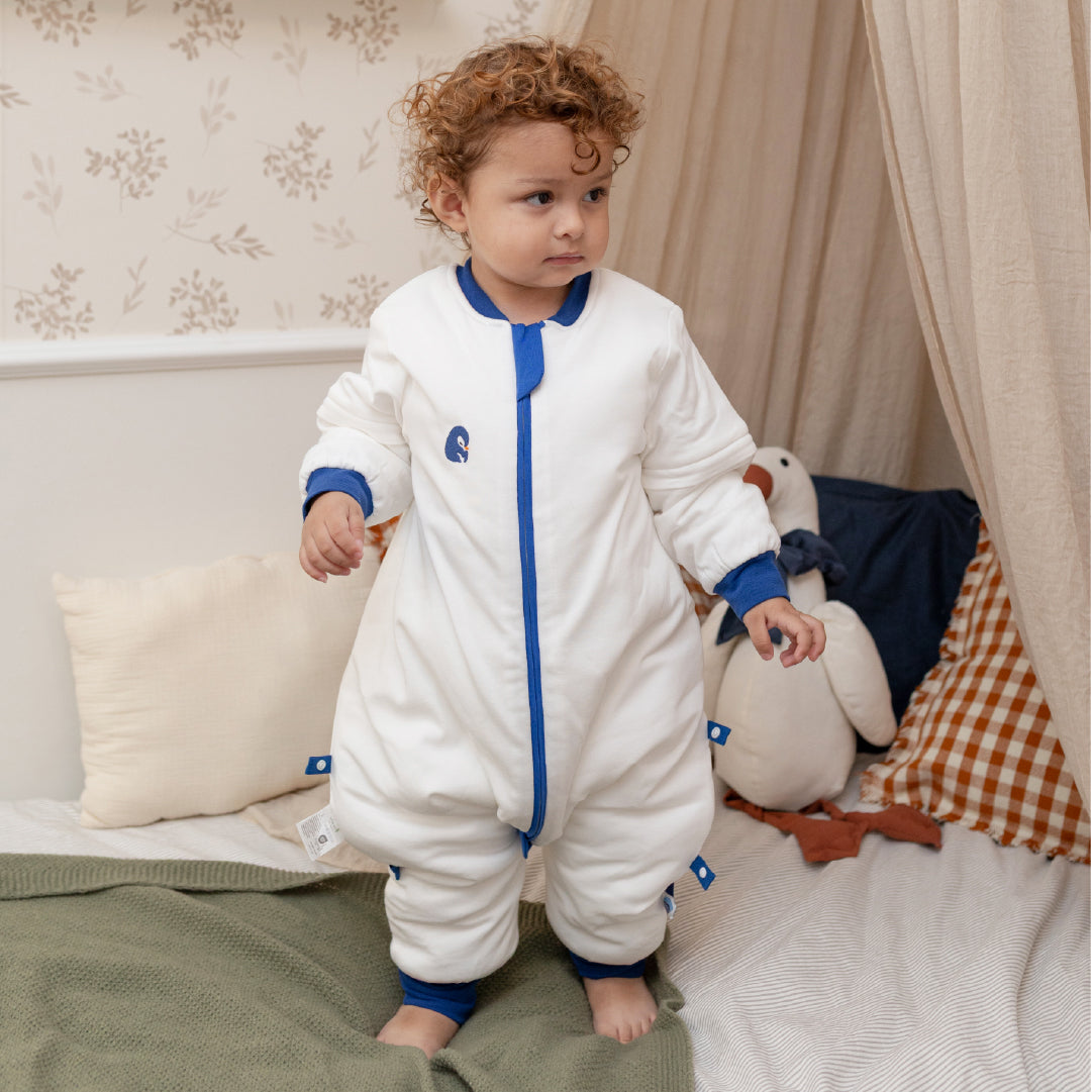 boy standing in blue penguin slaapzak 